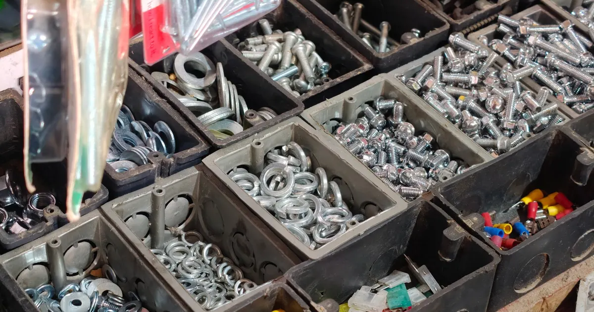 Black storage bins of nuts, bolts and washers sorted by size, the kind of lines listed in a bill of materials for manufacturing
